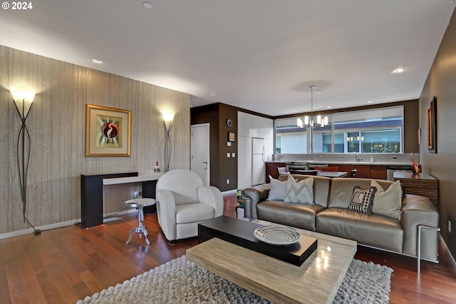 living room with an inviting chandelier, sink, and dark wood-type flooring