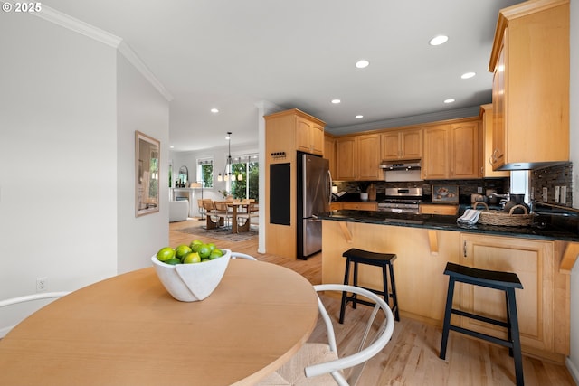 2834 SE Franklin St, Portland, OR 97202 - kitchen with stainless steel appliances, a peninsula, under cabinet range hood, crown molding, and light wood finished floors