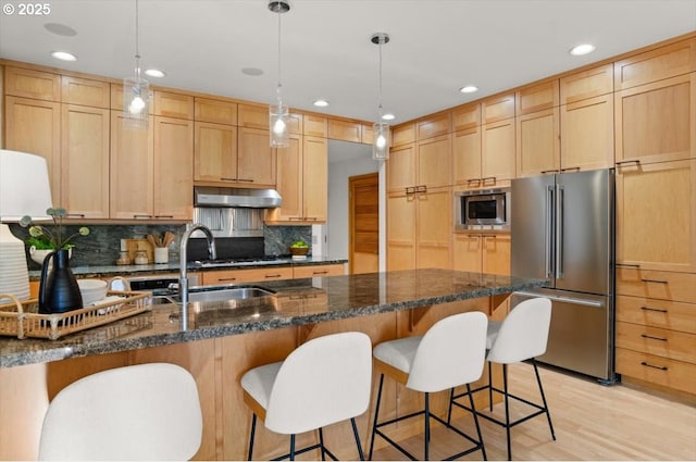 kitchen featuring pendant lighting, light brown cabinetry, dark stone countertops, decorative backsplash, and stainless steel appliances