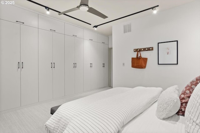 carpeted bedroom with ceiling fan and rail lighting