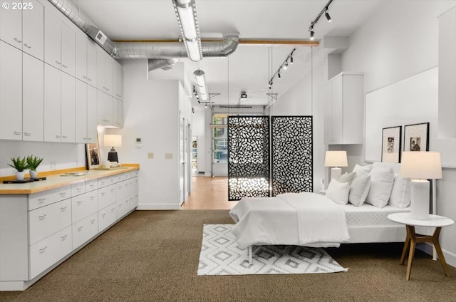 carpeted bedroom featuring a high ceiling and track lighting