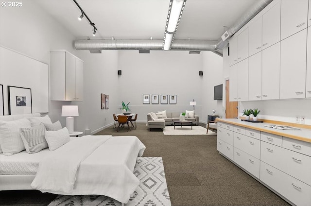 carpeted bedroom featuring a towering ceiling and rail lighting