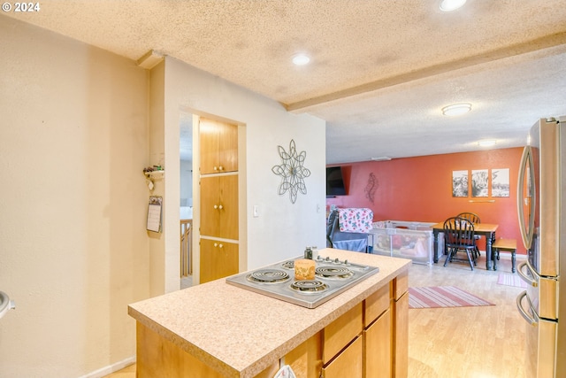 kitchen with a center island, light wood-type flooring, stainless steel appliances, and a textured ceiling