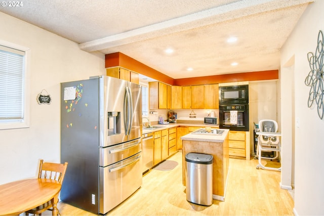 kitchen featuring a textured ceiling, light wood-type flooring, a kitchen island, and black appliances