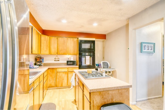 kitchen with black appliances, a kitchen island, and a textured ceiling