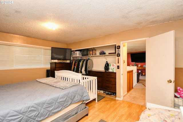 bedroom featuring a textured ceiling, light hardwood / wood-style floors, and a closet