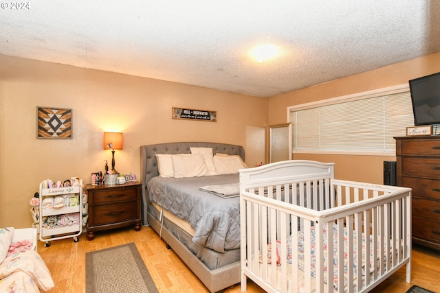 bedroom with a textured ceiling and light wood-type flooring