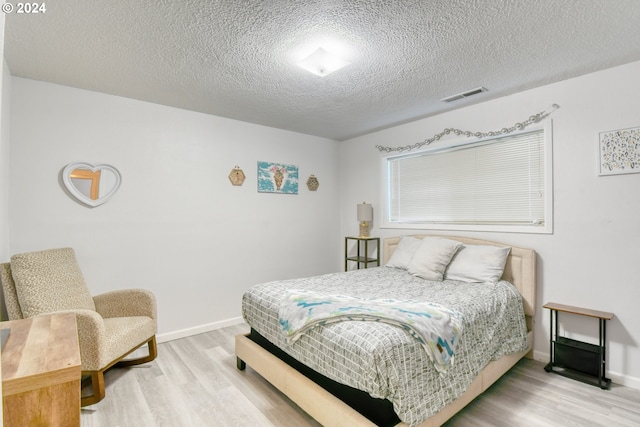 bedroom with a textured ceiling and hardwood / wood-style flooring