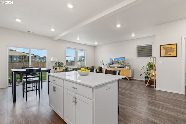 kitchen with white cabinetry, dark hardwood / wood-style flooring, a kitchen island, and beam ceiling