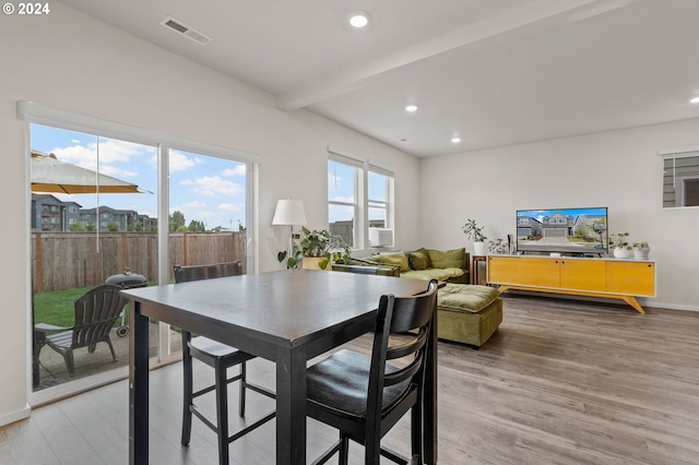 dining room featuring beamed ceiling and light hardwood / wood-style flooring