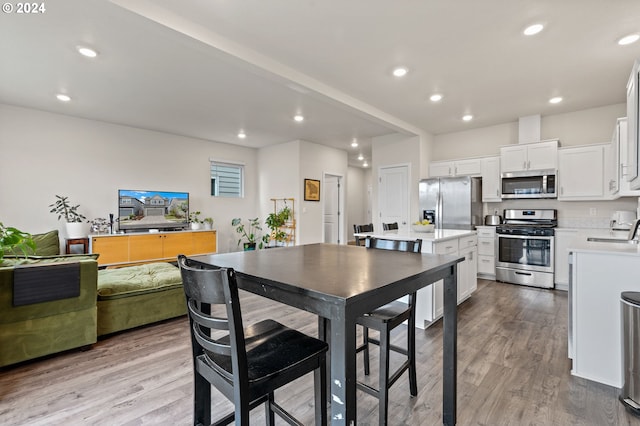 kitchen with light wood-type flooring, appliances with stainless steel finishes, white cabinetry, and sink