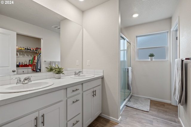 bathroom with a shower with door, vanity, wood-type flooring, and a textured ceiling