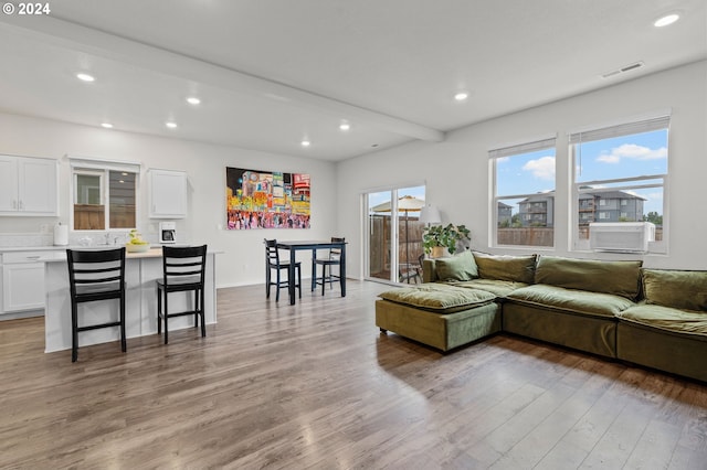 living room with cooling unit, wood-type flooring, and beamed ceiling