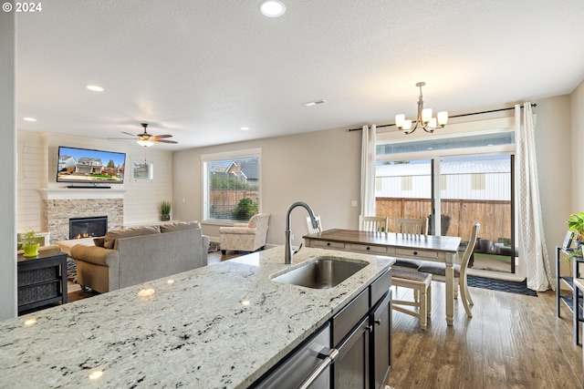 kitchen featuring light stone countertops, dark hardwood / wood-style flooring, sink, a fireplace, and hanging light fixtures