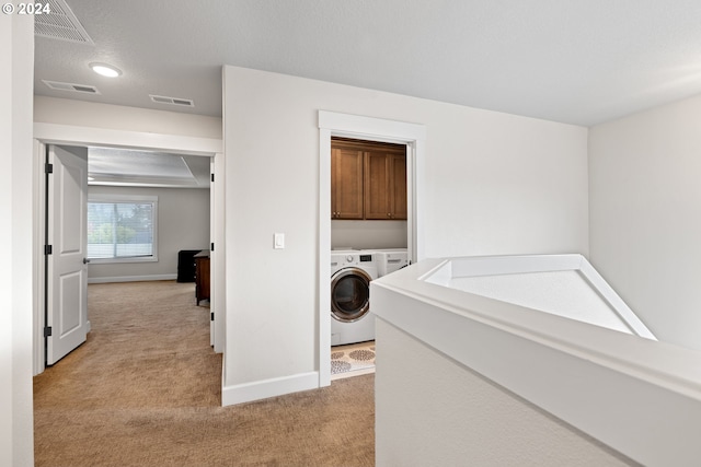 laundry area featuring independent washer and dryer, a textured ceiling, and light colored carpet