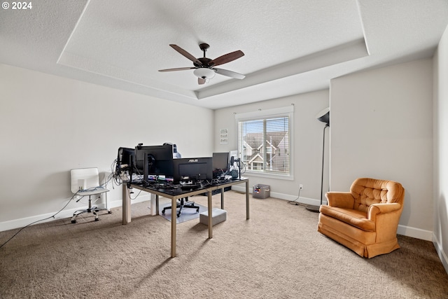 carpeted home office with ceiling fan, a raised ceiling, and a textured ceiling