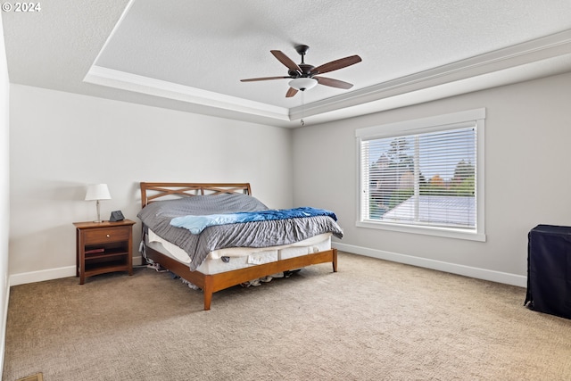 bedroom featuring light carpet, a textured ceiling, a tray ceiling, and ceiling fan