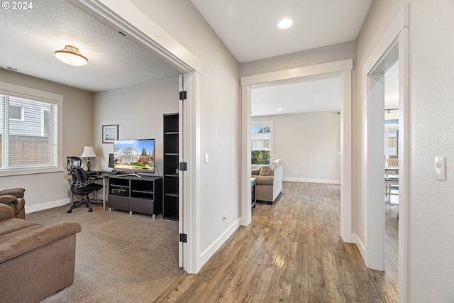 corridor with a textured ceiling and hardwood / wood-style flooring