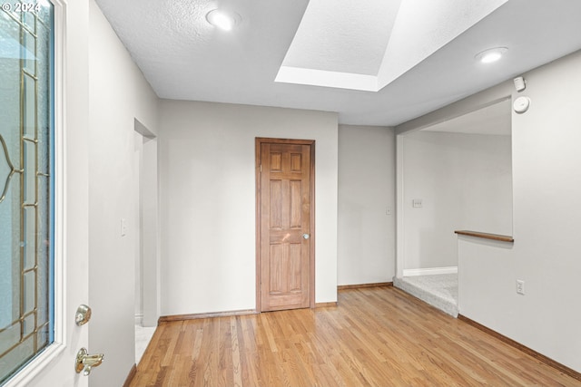 unfurnished room featuring light hardwood / wood-style flooring and a textured ceiling