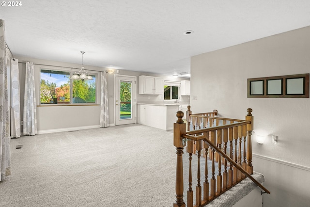 interior space featuring an inviting chandelier, light carpet, and a textured ceiling