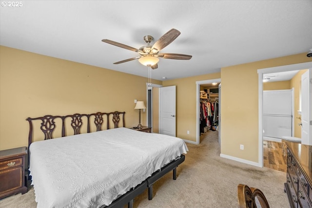 bedroom with a ceiling fan, a closet, baseboards, a walk in closet, and light colored carpet