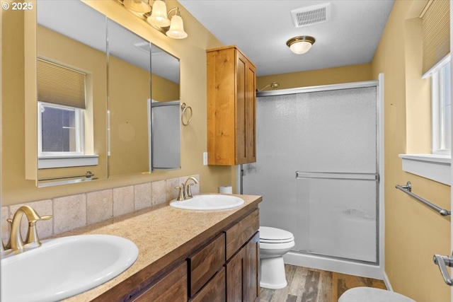 bathroom with a sink, toilet, visible vents, and wood finished floors