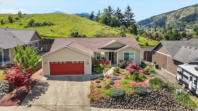 view of front of house featuring central air condition unit, a mountain view, driveway, and a garage