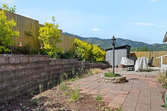 view of patio with a storage shed, a mountain view, an outbuilding, and a fenced backyard