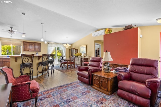 living area featuring ceiling fan with notable chandelier, wood finished floors, a wall unit AC, and vaulted ceiling