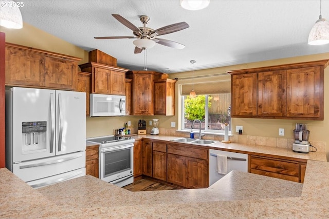 kitchen featuring light countertops, brown cabinetry, a sink, and white appliances