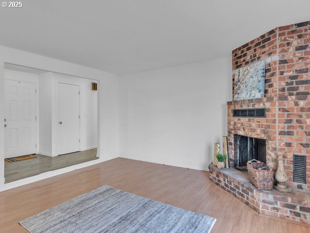 unfurnished living room featuring a brick fireplace and hardwood / wood-style flooring