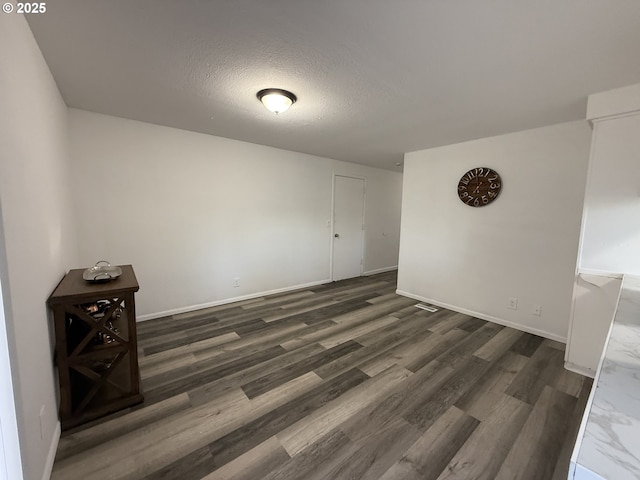 spare room featuring dark wood-type flooring and a textured ceiling