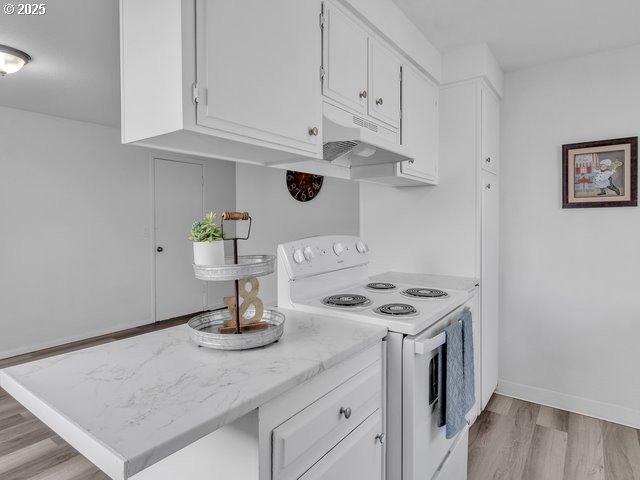 kitchen featuring white cabinetry, light hardwood / wood-style floors, and electric range