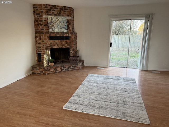 living room with a brick fireplace and wood-type flooring