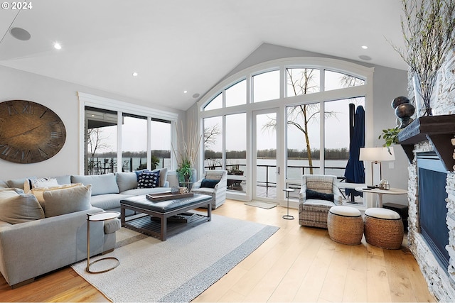 living room featuring a water view, light hardwood / wood-style floors, and vaulted ceiling