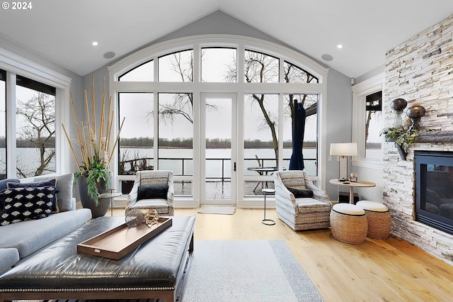 living room with a water view, light hardwood / wood-style floors, plenty of natural light, and a fireplace