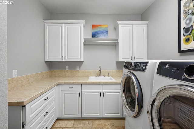 clothes washing area with cabinets, sink, and washing machine and dryer