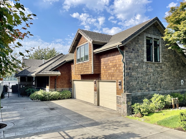 15421 SE Rivershore Dr, Vancouver, WA 98683 - view of side of property featuring stone siding, concrete driveway, fence, and an attached garage