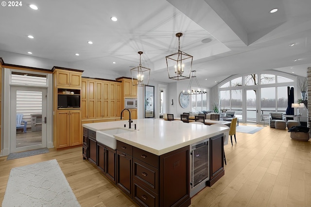 kitchen featuring a chandelier, light hardwood / wood-style floors, a kitchen island with sink, sink, and beverage cooler