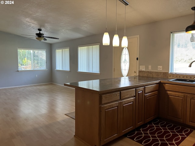 kitchen with sink, kitchen peninsula, hardwood / wood-style flooring, and a textured ceiling