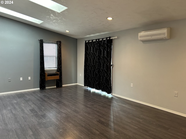 empty room with lofted ceiling with skylight, dark wood-type flooring, and a wall mounted AC