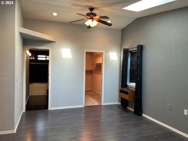 interior space with ceiling fan, vaulted ceiling, and dark hardwood / wood-style flooring