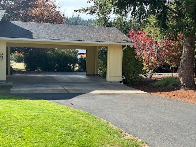 exterior space with a carport and a lawn