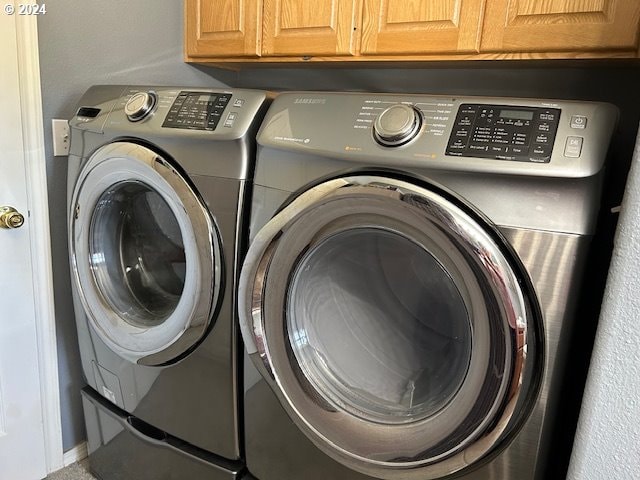 clothes washing area with cabinets and washing machine and dryer