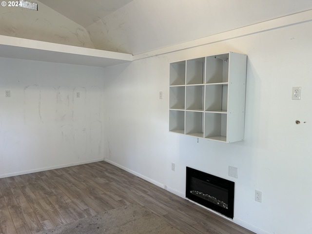 unfurnished living room with hardwood / wood-style floors and vaulted ceiling