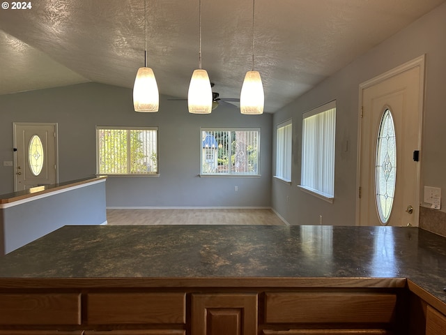 kitchen with lofted ceiling, a textured ceiling, and hanging light fixtures