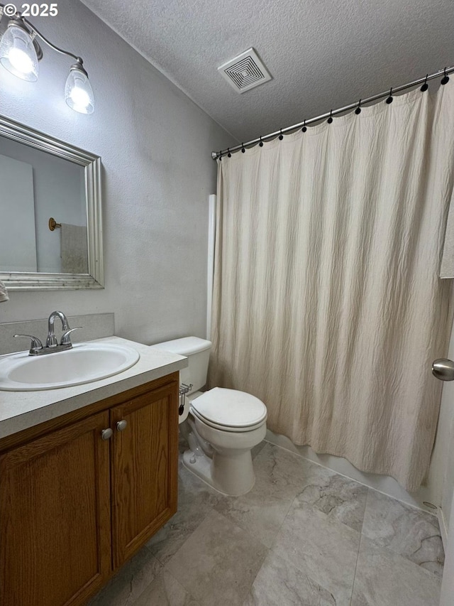 bathroom featuring vanity, toilet, and a textured ceiling