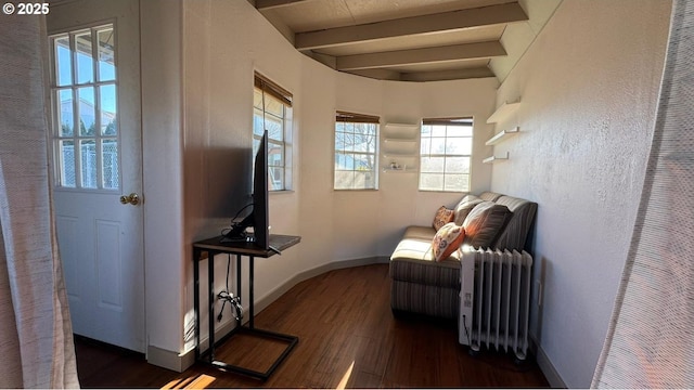 living area with dark wood-type flooring, radiator, and beam ceiling