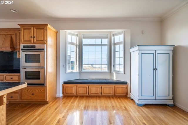 kitchen featuring light wood-type flooring, tasteful backsplash, double oven, crown molding, and custom exhaust hood