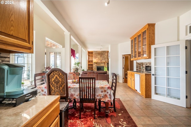 dining room with light tile patterned floors and a stone fireplace